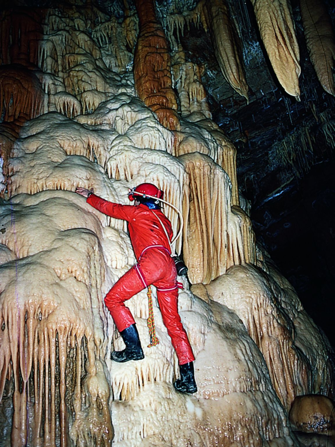 un spéléologue sur une stalactite géante (grotte de l’Hérault, France)